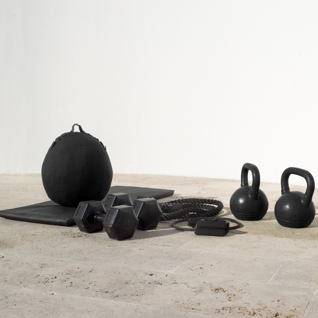kettle bells, dumbbells and a mat on a grey floor